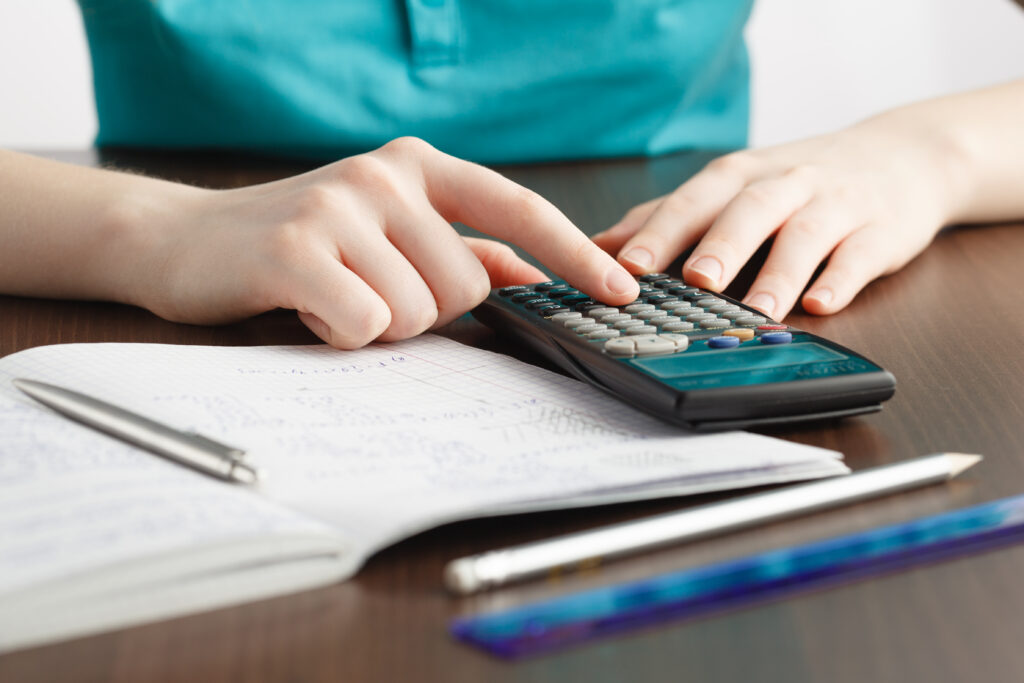 mujer con calculadora hace cuentas en un cuaderno